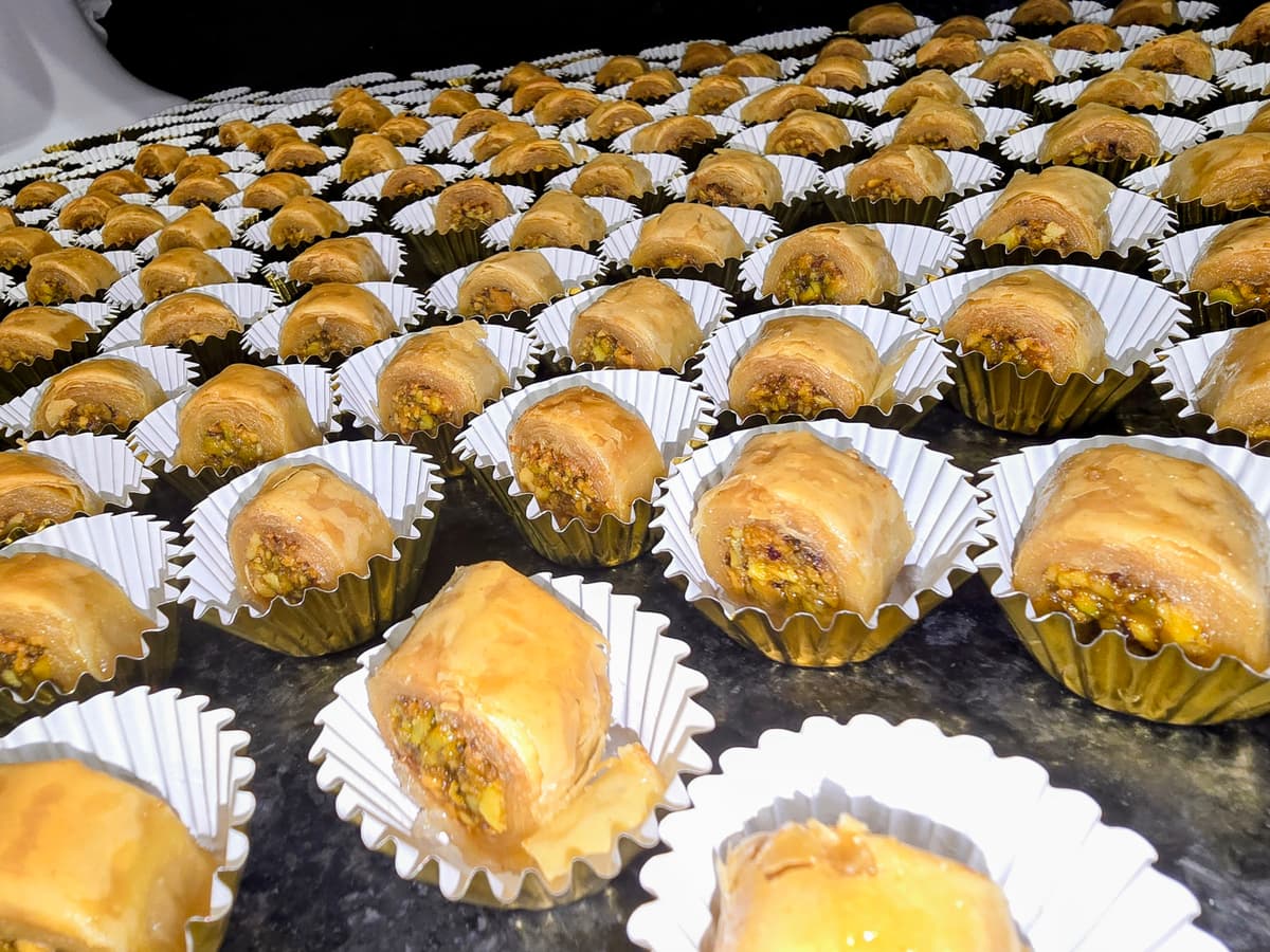 endless baklavas in gold foil cups laid across black granite countertop